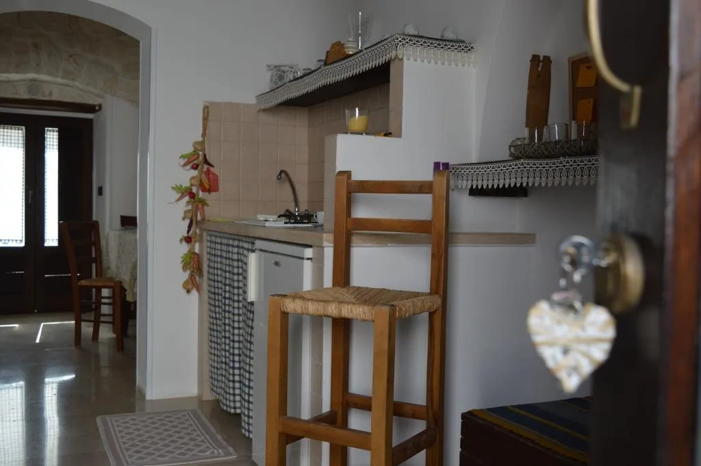 Cucina in trullo con sgabello in legno, angolo cottura e decorazioni rustiche