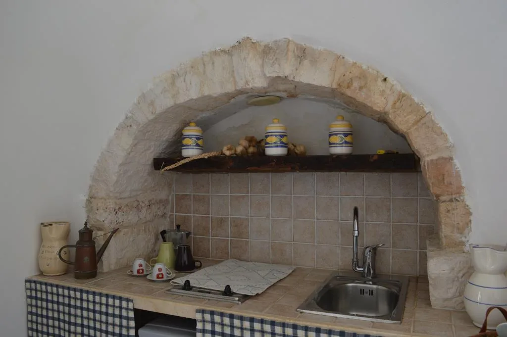 Cucina con arco in pietra, lavello e barattoli decorativi in ceramica