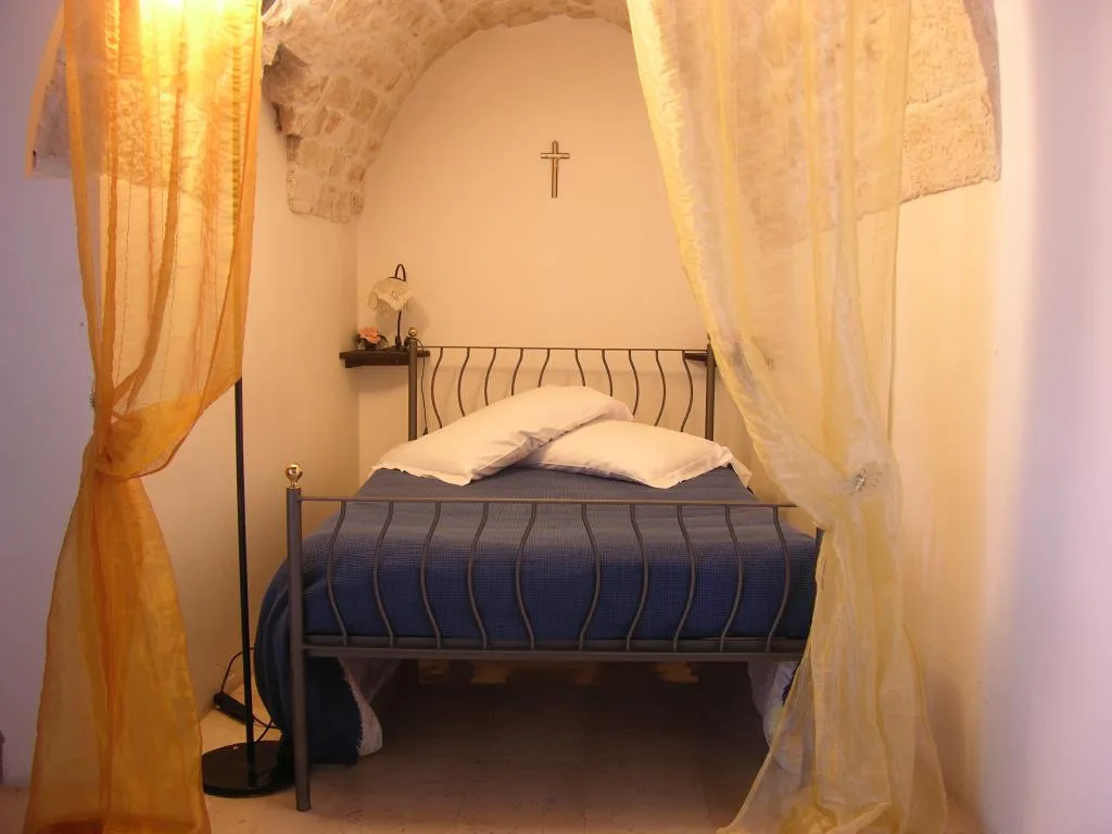 Camera in trullo con volta in pietra, letto con copriletto blu e tende gialle