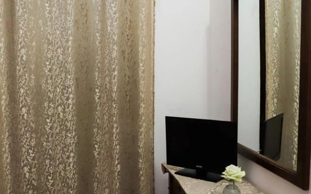Dettaglio camera con televisore, specchio e tende beige