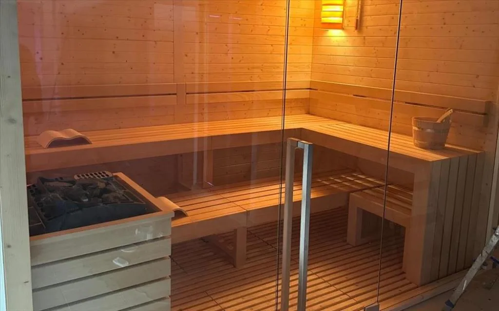 Sauna finlandese in legno con panche e stufa a pietre
