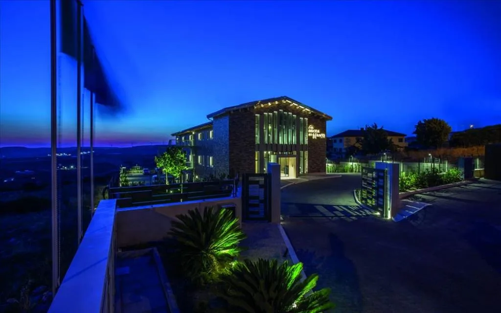 Hotel illuminato di sera con cielo blu crepuscolo, palme e ingresso illuminato