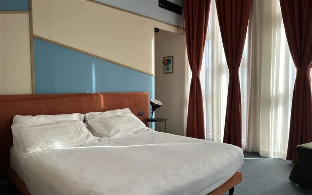 Camera luminosa con letto matrimoniale e ampie finestre con tende rosse