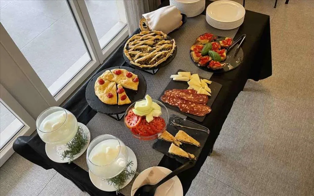 Buffet con specialità locali salate, salumi, formaggi e focacce su tavolo nero