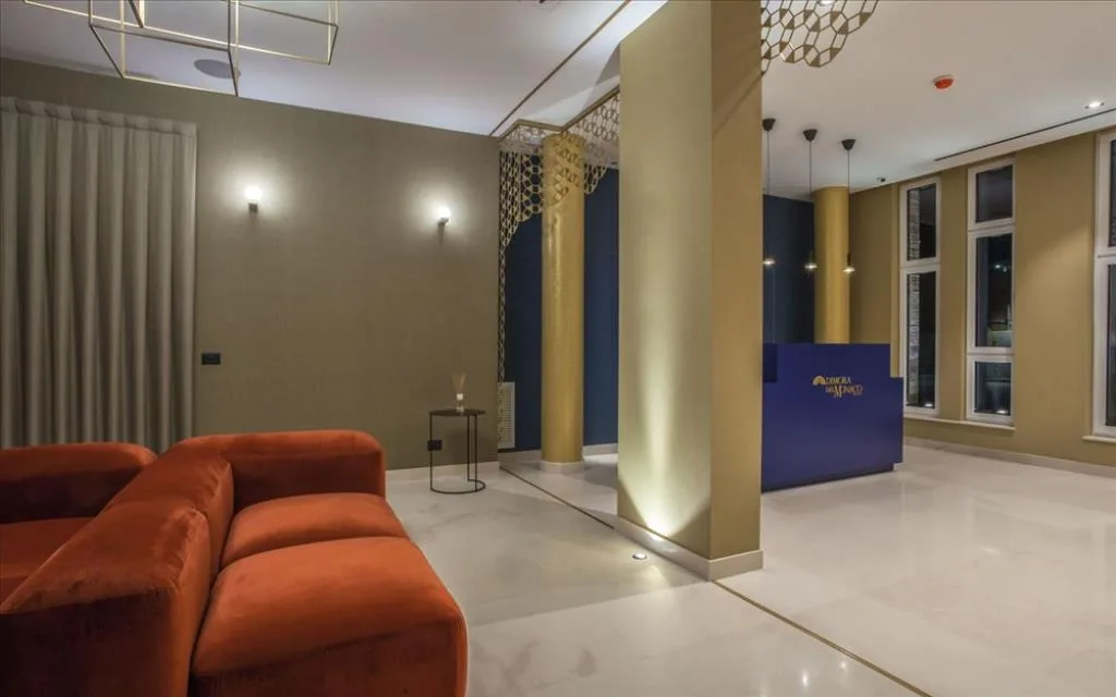Hall dell'hotel con reception blu, divano rosso e colonne dorate