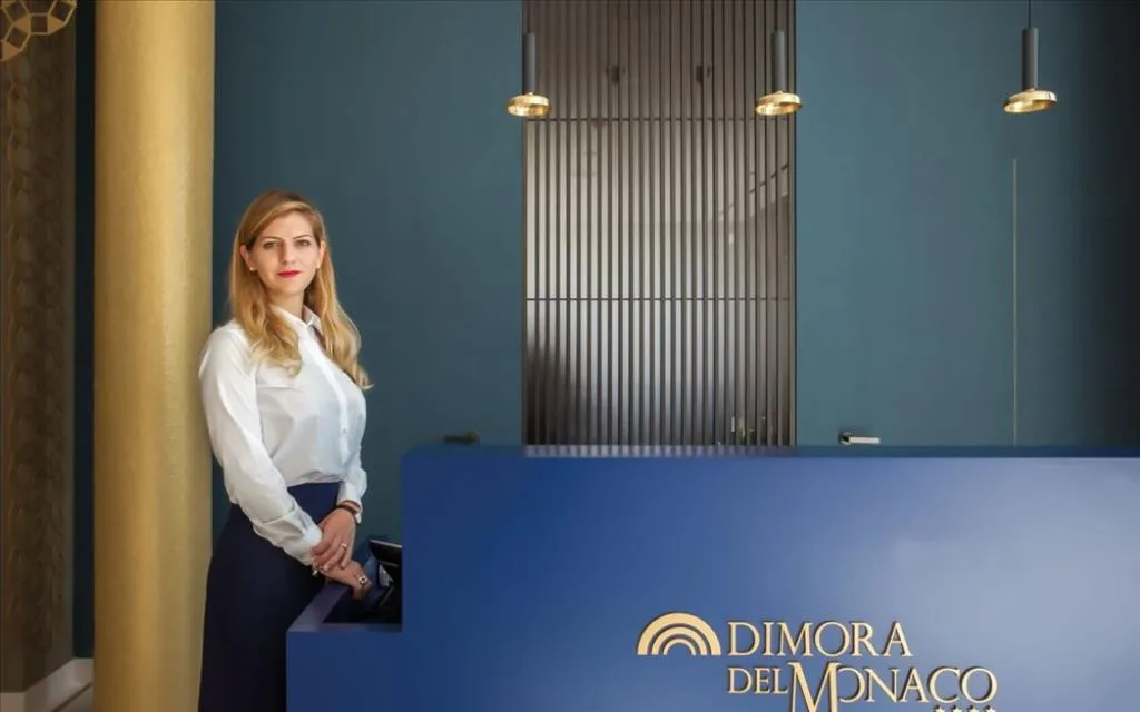 Addetta alla reception in accoglienza dietro il bancone Dimora del Monaco