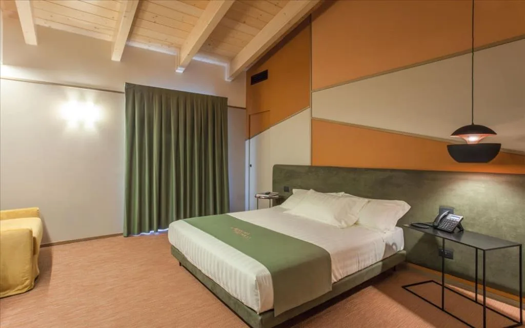 Camera con soffitto in legno, letto matrimoniale, tenda verde e poltrona gialla