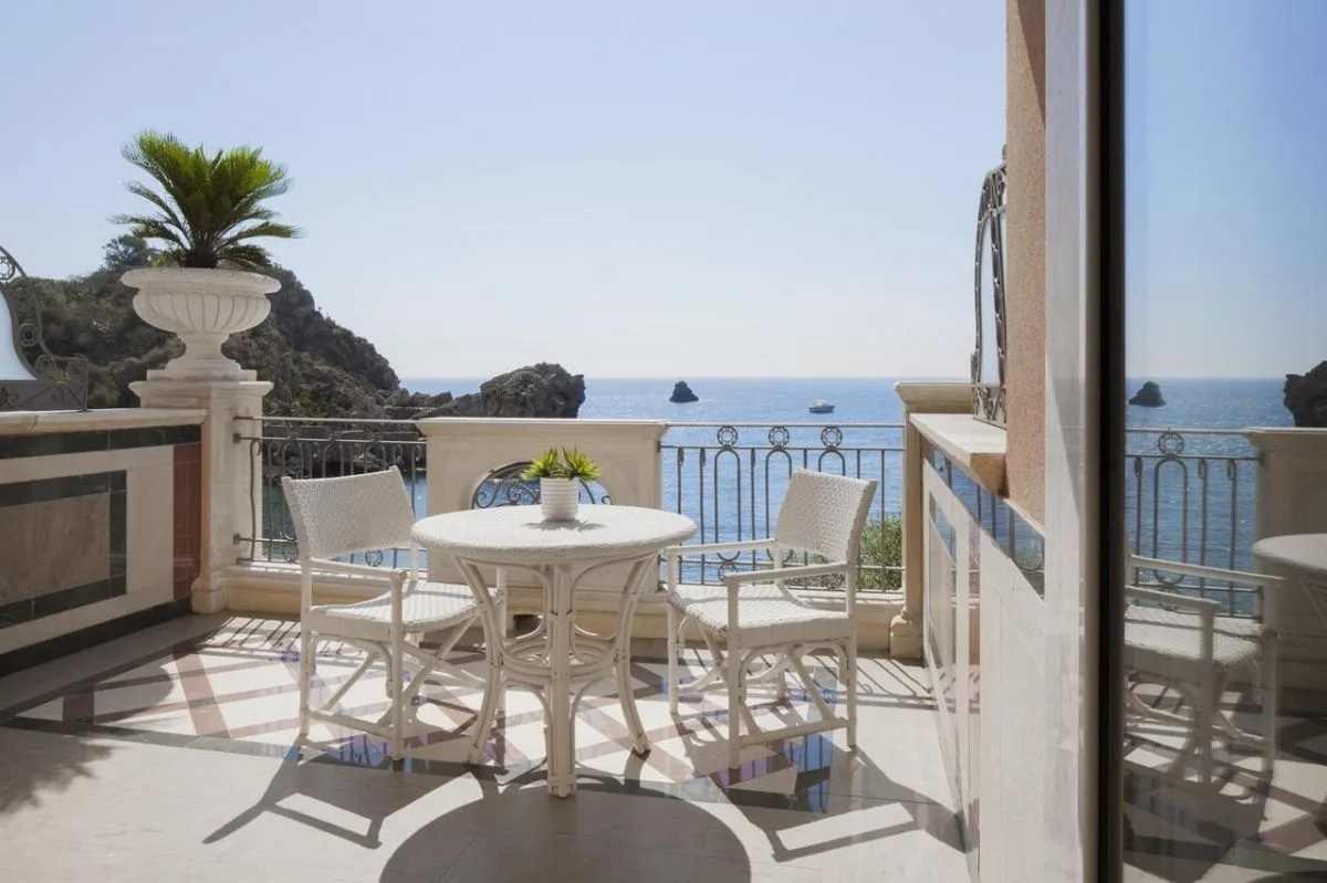 Balcone privato con tavolino e sedie bianche affacciato sul mare e sulla scogliera