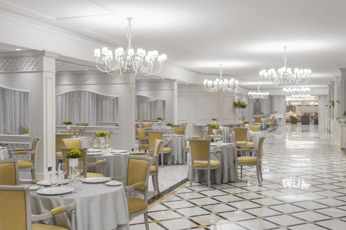 Sala ristorante elegante con tavoli rotondi, sedie gialle e lampadari a sospensione