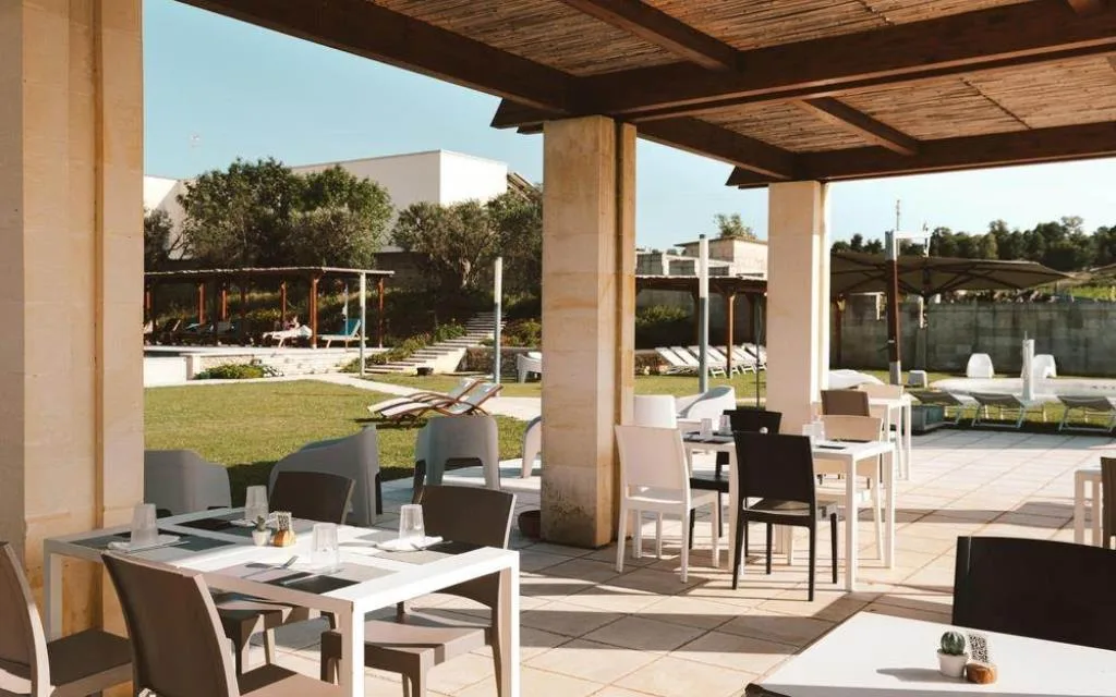Area pranzo esterna coperta con vista sul giardino e sulla piscina