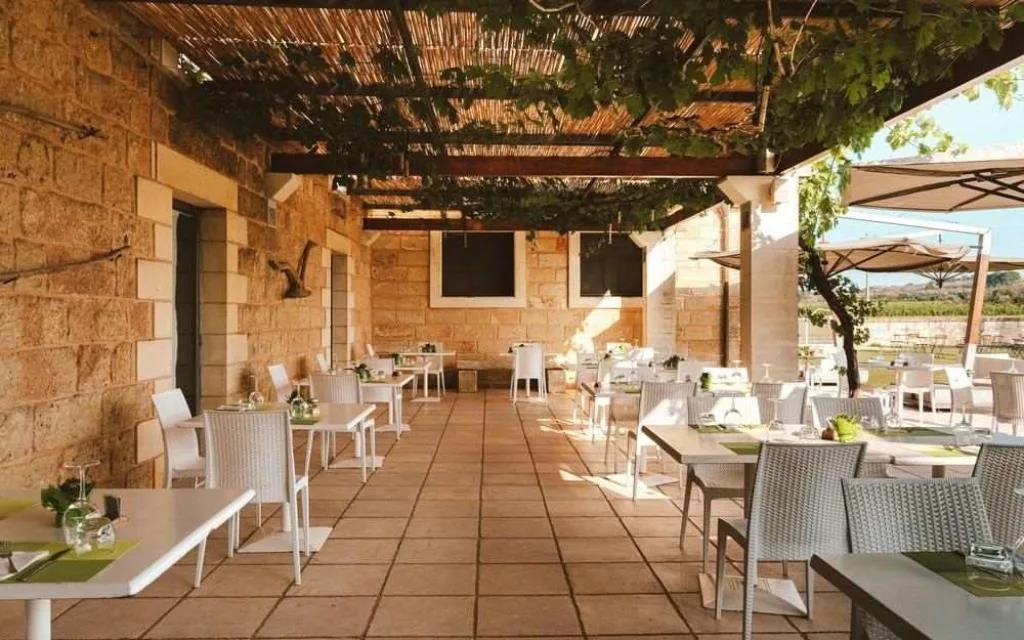 Portico in pietra del ristorante con tavoli apparecchiati e pergolato di vite
