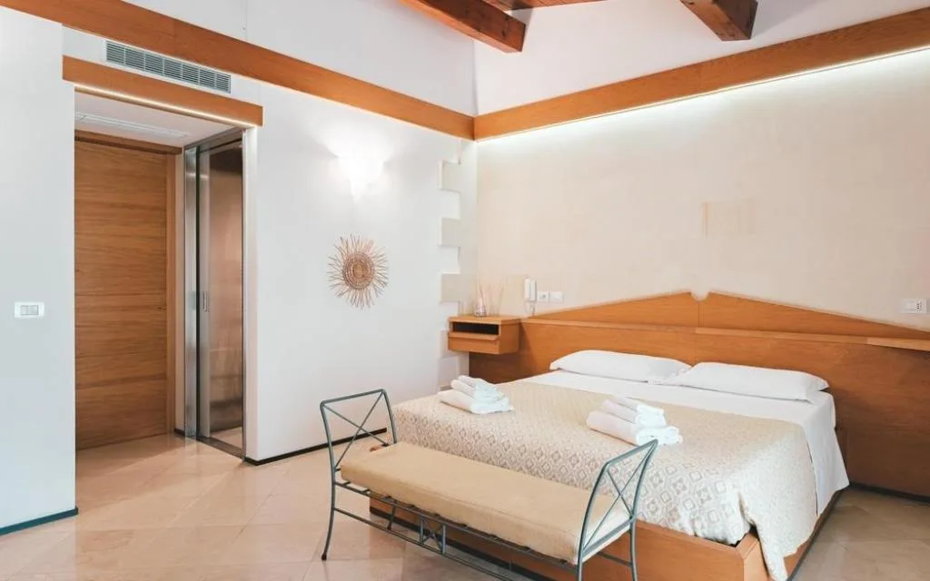 Camera con letto matrimoniale, arredi in legno e travi a vista
