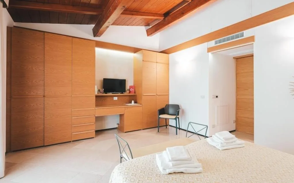 Dettaglio camera con armadiatura in legno, TV e scrivania