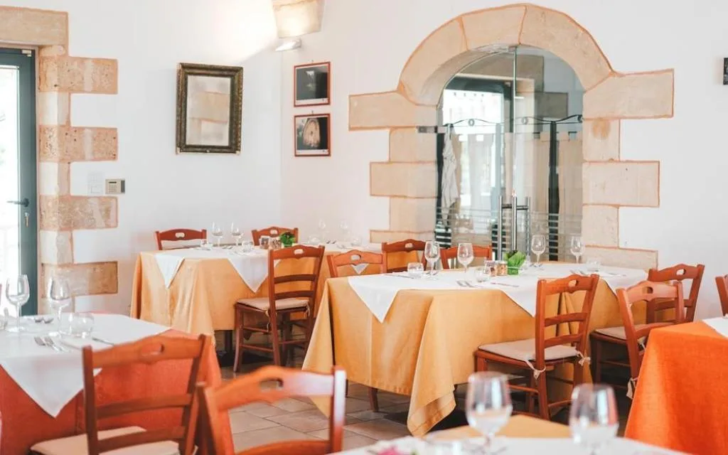 Sala da pranzo interna con arco in pietra e tavoli con tovaglie gialle
