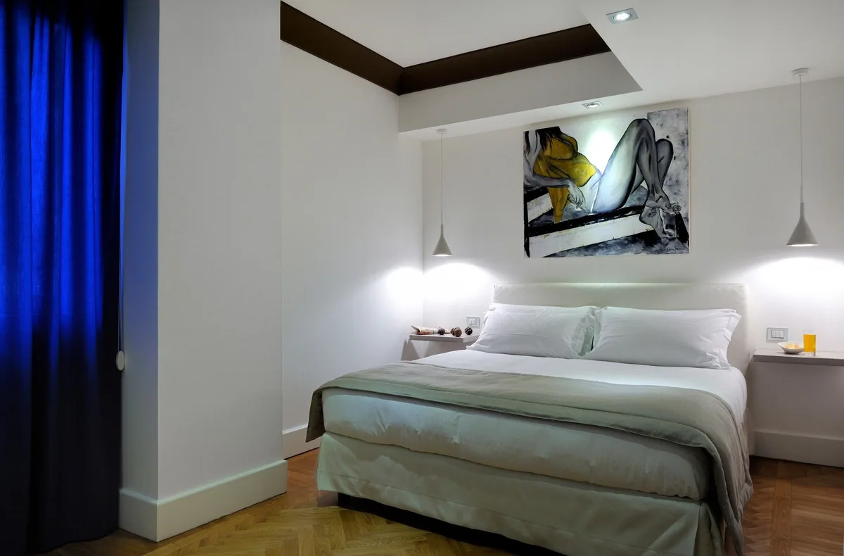 Camera matrimoniale moderna con letto bianco, dipinto artistico e tenda blu