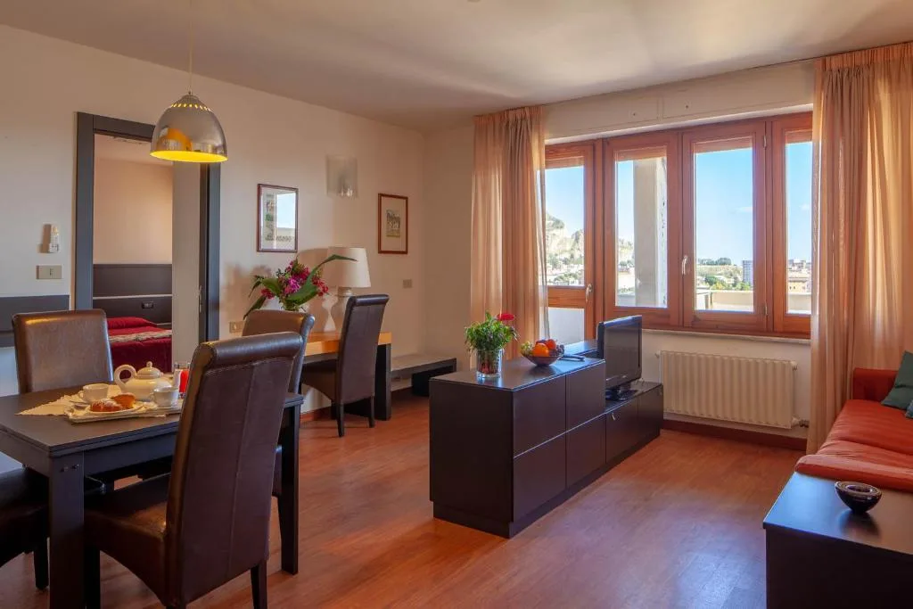 Soggiorno di un appartamento con tavolo da pranzo, mobile TV e finestre con vista sulle montagne