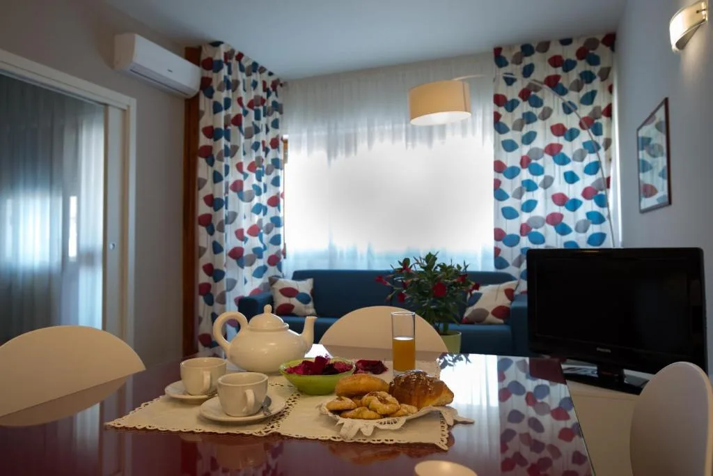 Tavolo da pranzo con colazione servita e soggiorno con divano blu e tende colorate