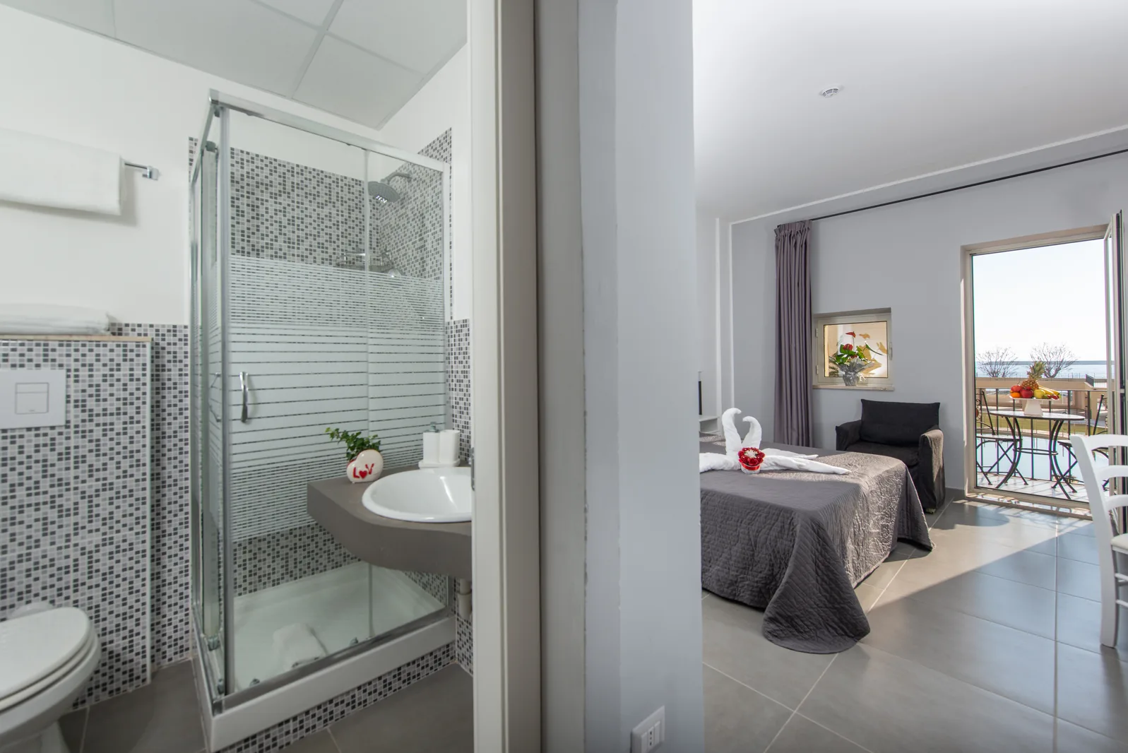 Camera con bagno privato dotato di doccia e lavabo, letto matrimoniale e balcone con vista