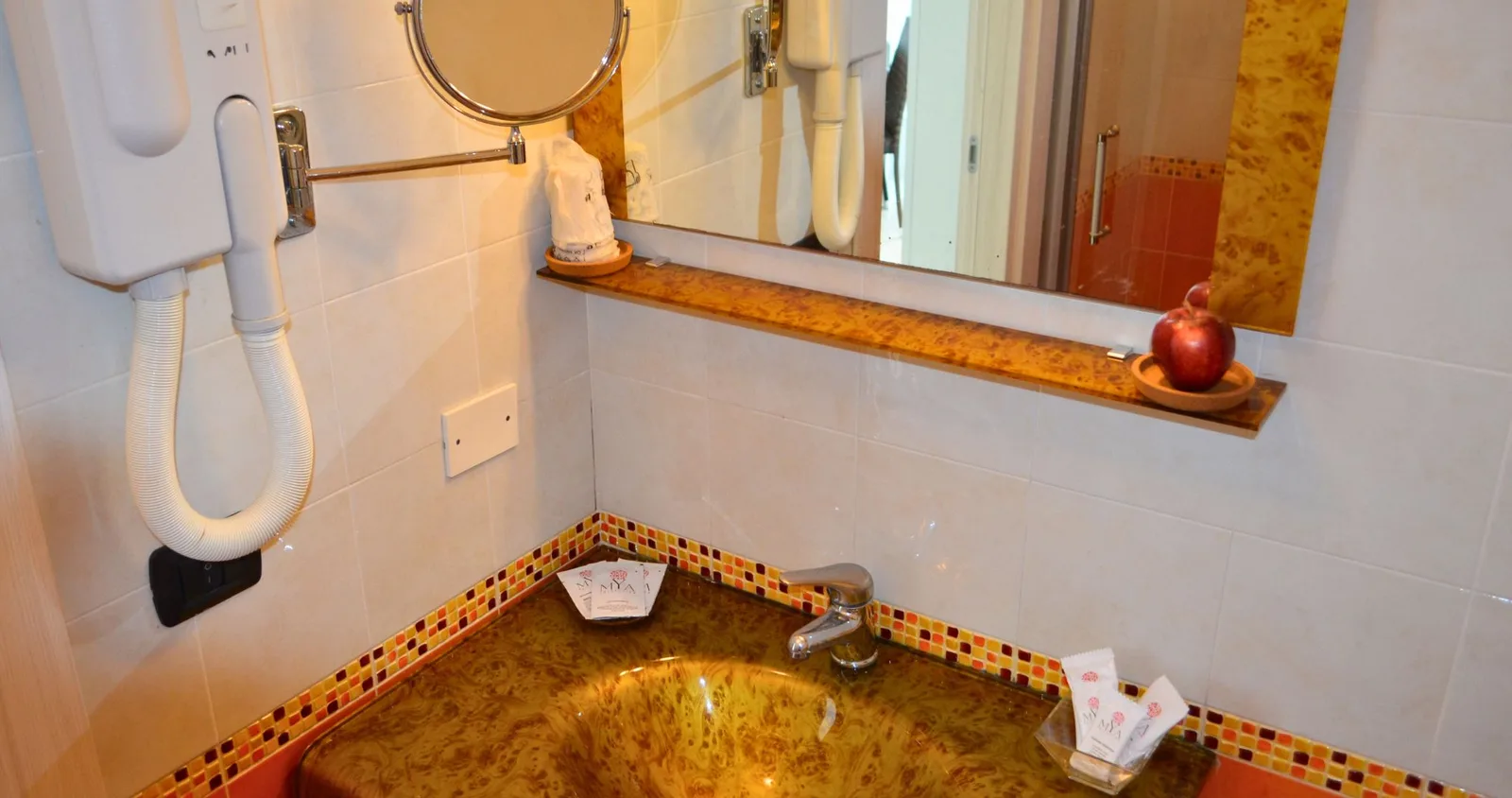 Bagno dell'hotel con lavabo in marmo ambrato, specchio, phon e set di cortesia