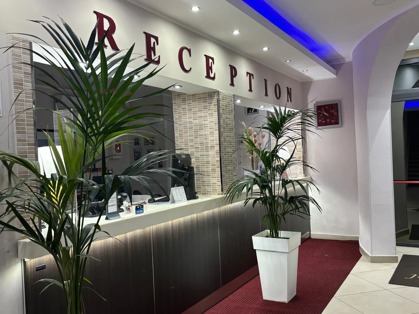 Reception dell'hotel con bancone in legno e piante decorative