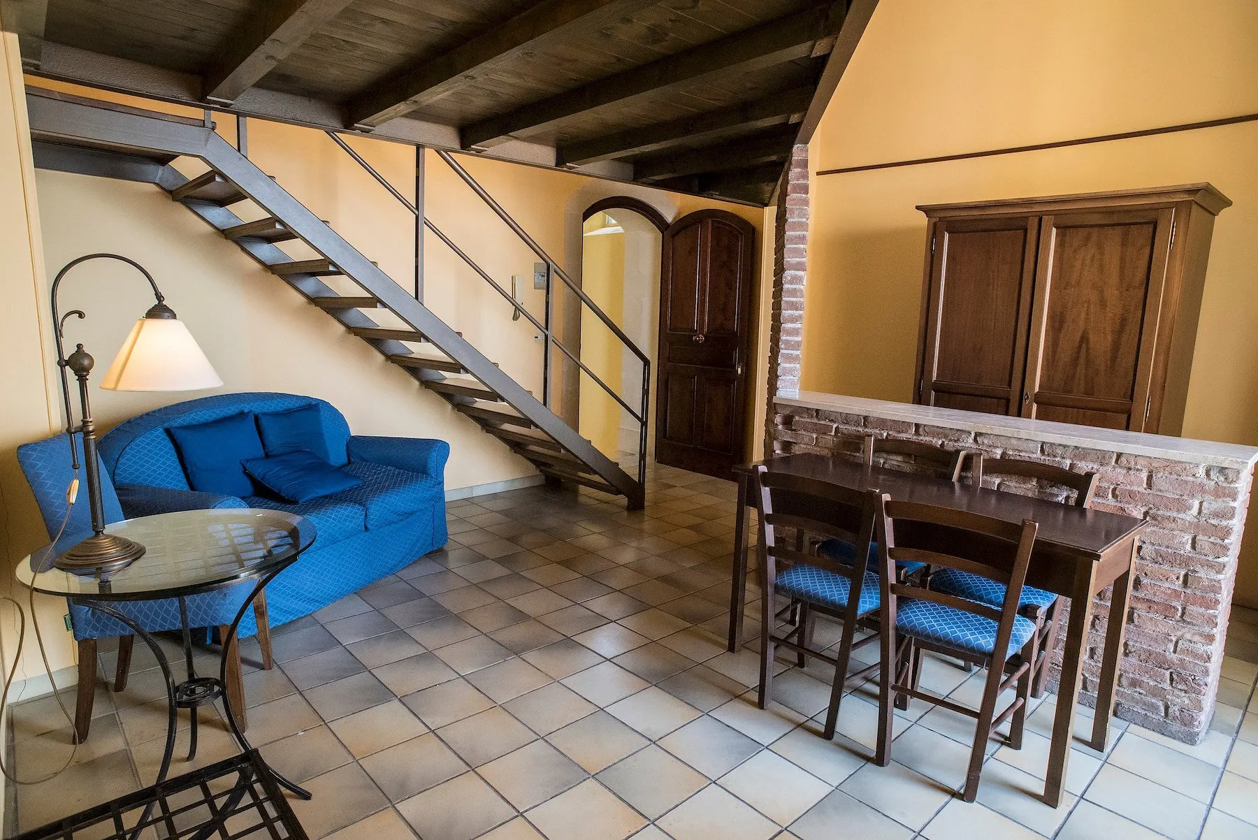 Soggiorno su due livelli con scala interna, divano blu e tavolo in legno