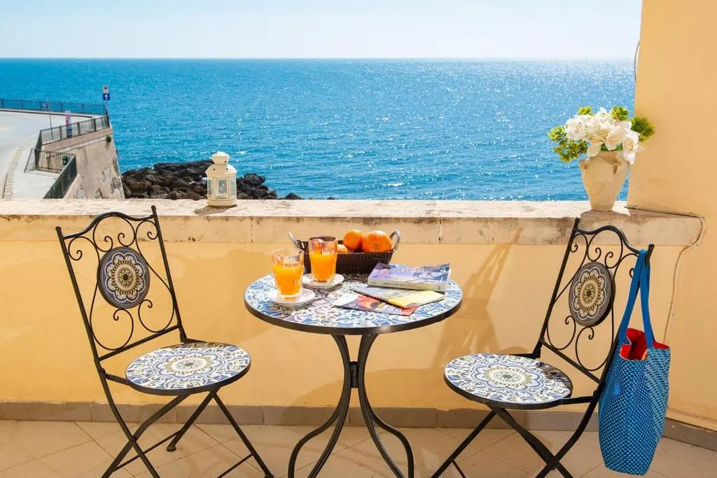 Balcone con tavolino in mosaico, succhi e frutta affacciato sul mare