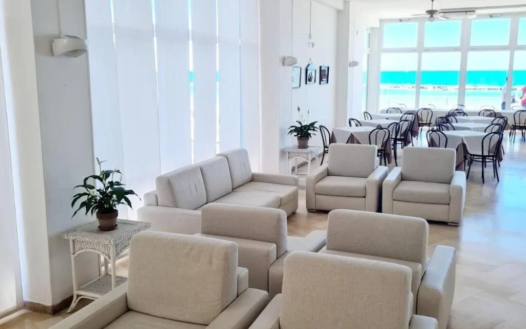 Salotto luminoso con divani chiari e sala da pranzo con vista mare