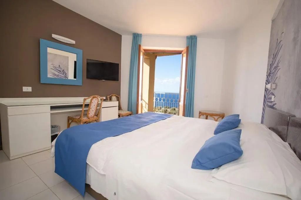 Camera matrimoniale con dettagli azzurri, scrivania e balcone con vista mare